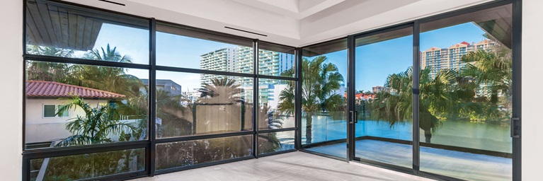 ceiling to floor windows and door with views of ocean